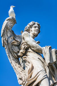 Low angle view of statue against blue sky
