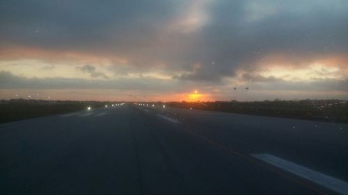 Country road against cloudy sky at sunset