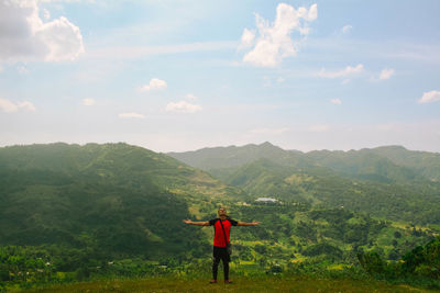 Man standing on grass against mountains and sky