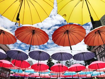 Low angle view of multi colored umbrellas hanging against sky