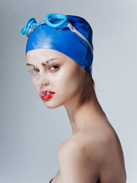 Portrait of shirtless woman against blue background