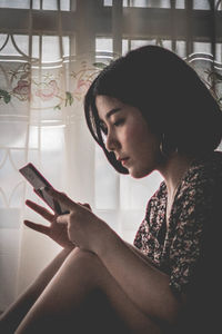 Young woman using smart phone at home