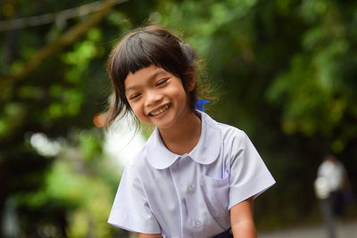Close-up of smiling girl against trees