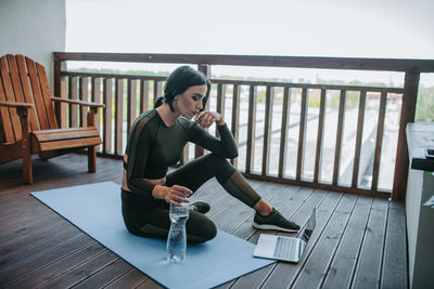 Young woman using mobile phone while sitting on table