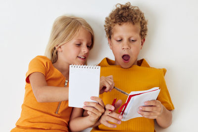 Boy and girl writing on diary against white background