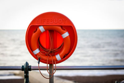 Close-up of coin-operated binoculars by sea against sky