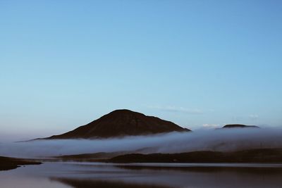 Scenic view of lake and mountains against clear blue sky