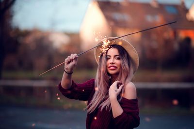 Portrait of young woman holding umbrella while standing at riverbank