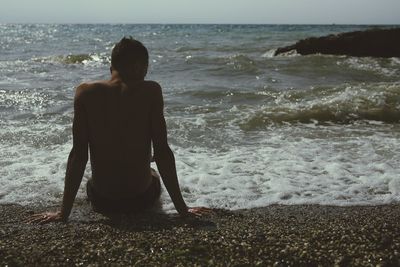 Rear view of man standing on beach against clear sky