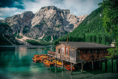 Stilt house at lake by mountains against sky