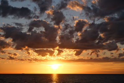 Scenic view of sea against dramatic sky during sunset