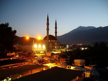 Illuminated mosque in city against clear sky at dusk