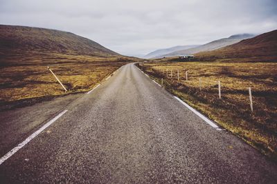 Empty road amidst landscape against sky