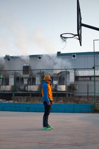 Full length of young man at basketball court against sky