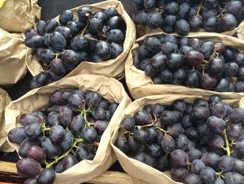 High angle view of red grapes in paper bags for sale at market stall