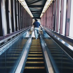 Rear view of man walking on escalator