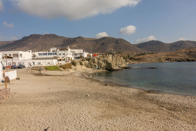 Scenic view of beach by buildings against sky