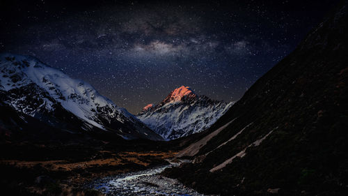 Scenic view of snowcapped mountains against star field