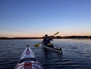 Woman sitting on boat in lake against clear sky