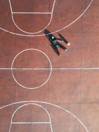 Aerial view of man lying on floor at basketball court