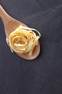 Close-up of tagliatelle in wooden spoon on slate