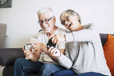 Happy couple playing video game while sitting on sofa at home