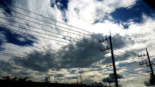 Low angle view of electricity pylon against cloudy sky