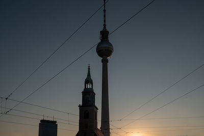 Low angle view of communications tower and buildings against sky