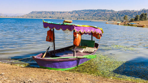 Boat moored on lake against sky