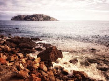 Scenic view of rocks on beach against sky