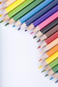 High angle view of colored pencils against white background