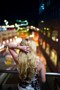 Rear view of woman in illuminated city at night