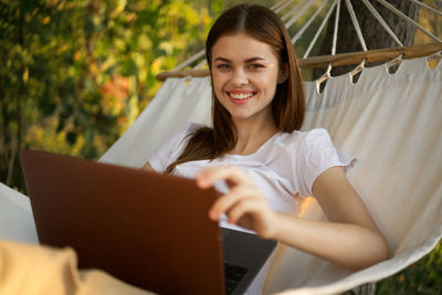 Portrait of young woman using laptop while sitting on sofa at home