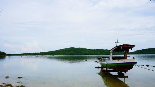 Boat moored in lake against sky