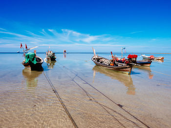 Boats moored on sea against blue sky