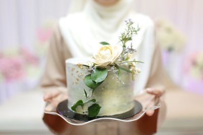 Midsection of bride holding wedding cake