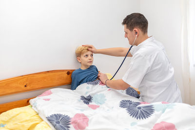 Boy looking away while sitting on bed