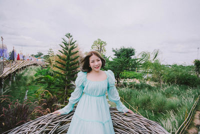 Portrait of smiling young woman standing against plants