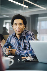 Portrait of confident businessman sitting at conference table in board room