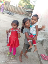 High angle view of siblings standing against wall