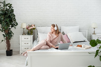 Woman listening music sitting on bed at home