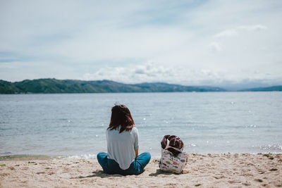 Rear view of woman sitting on beach