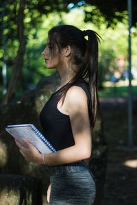 Side view of woman standing against tree