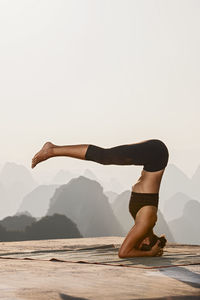 Beautiful woman practising yoga above the kast mountains of yangshuo