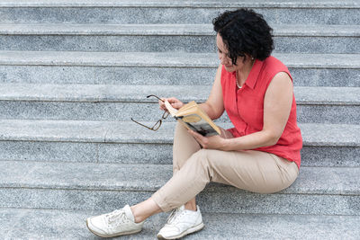 Young woman using mobile phone while sitting on staircase