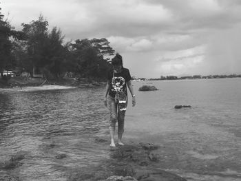 Woman standing by sea against sky