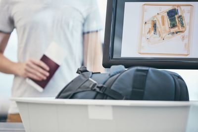 Midsection of man picking suitcase from conveyor belt