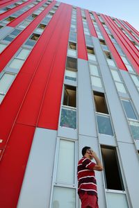 Low angle view of man talking on phone by building