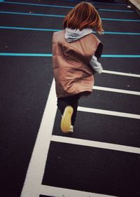 Rear view of girl running on zebra crossing