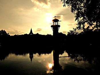 Reflection of silhouette trees in water at sunset